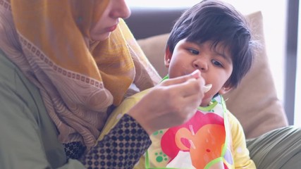 muslim mother feeding food baby child indoor 