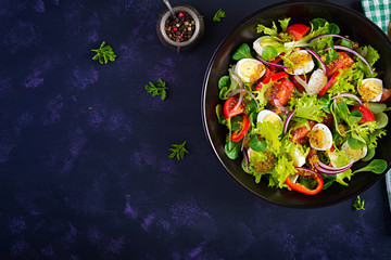 Fresh salad with vegetables tomatoes, red onions, lettuce and quail eggs. Healthy food and diet concept. Vegetarian food. Top view, overhead