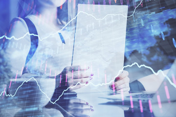 Double exposure of hands making notes with forex chart huds. Stock market concept.