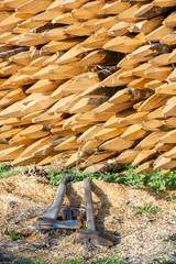 Stacked manually chopped wood into tree stakes with a sharpened end used for fencing with to axes lying in front of it.