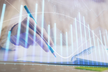 Financial forex graph displayed on hands taking notes background. Concept of research. Double exposure
