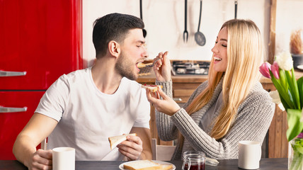 Beautiful young couple is eating sandwiches and smiling
