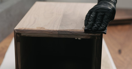 woodworker applying oil finish to black walnut storage box