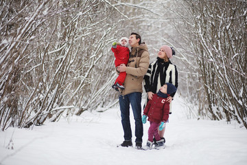 Fototapeta na wymiar Young family with children are walking in the winter park. Winter walk of parents with children. Walking on a holiday weekend in the winter.