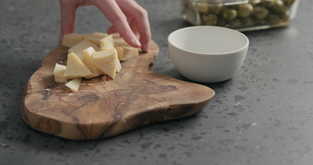 man slicing parmesan cheese on olive wood board