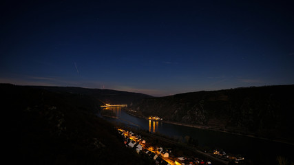 Night shot of the Rhine valley and under a starry sky. Reflections of illuminated houses on the River Rhine