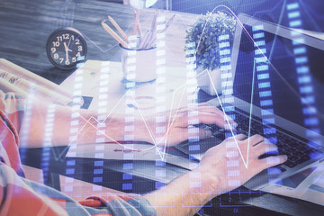 Double exposure of stock graph with businessman typing on computer in office on background. Concept...