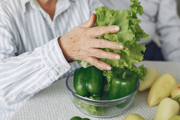 Couple in a kitchen. Grandparents sitting at home. Woman with vegetables
