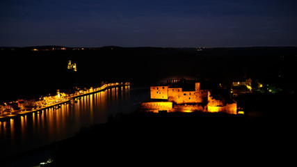 Night shot of Castle Rheinfels, colorfully illuminated, in front of the Rhine valley and under a starry sky. In background Castle Katz and the city of St.Goar