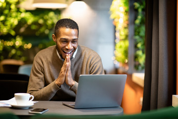 Afro businessman using laptop sitting at cafe