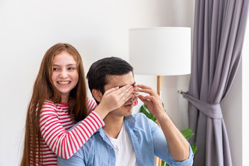 Daughter playing closing her father eye with hand, surprise greeting, while he is working at home with notebook computer