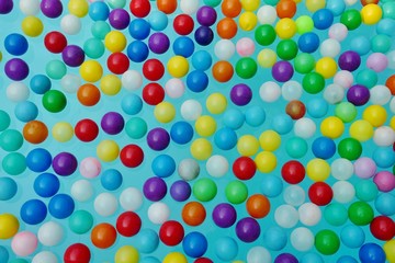 Colored plastic balls in a swimming pool, blue background