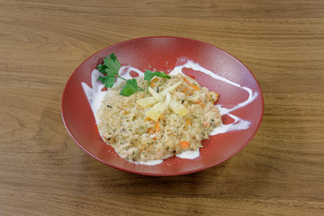 Restaurant food served on a red plate. Fish, cheese, salad, vegetables, sauce.