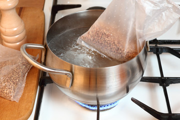 Adding plastic sachets into boiling water. Cooking buckwheat groats on gas stove.