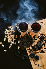 Chinese tea ceremony. Two cups of puer pu erh old aroma tea and snacks - peanut and prunes at tea board