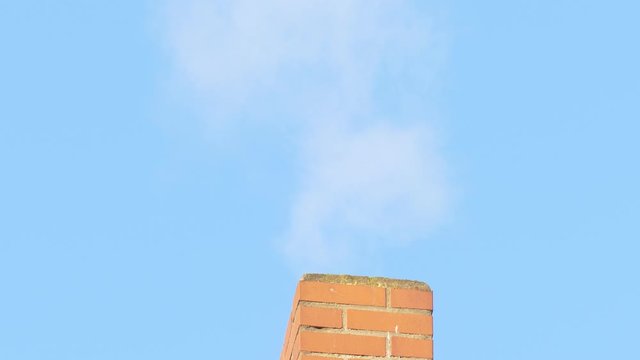 Rauchender Schornstein aus Backstein, Blauer Himmel