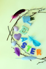 Easter decoration for the holiday, a wreath of eggs, hearts, pussy-willow branches on a bright background, top view
