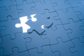 Missing piece of jigsaw puzzle with light glow, business concept for completing the final puzzle piece