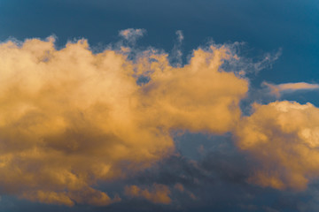 Stunning fluffy thunderstorm clouds illuminated by disappearing rays at sunset and dark cumulonimbus floating across sunny blue sky to change season weather. Natural abstract meteorology background.