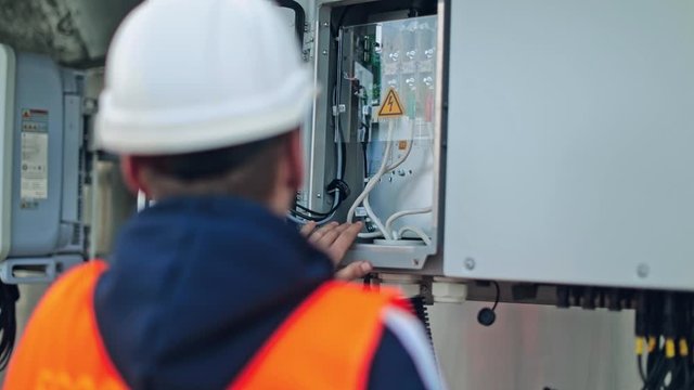 Electrician checks the wires of electric system. Male engineer controls the operation of the power system on a transformer.