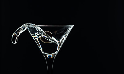 Silhouette of martini with green olives on a black background.