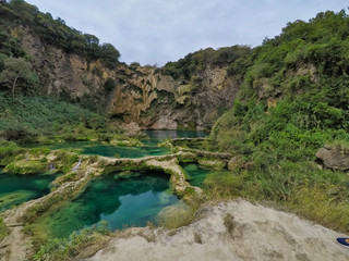 Rear of a woman standing over the rock stretching her hands and enjoying the waterfall, waterfall...