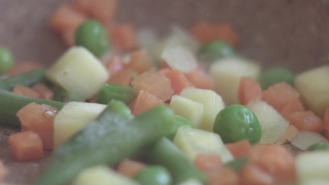 Vegetables mix frying on a pan stiring with spatula closeup
