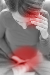 Pregnant tired exhausted woman with stomach and head issues at home on a couch, being sick.