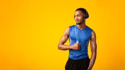 Handsome black sportsman with jumping rope and headset