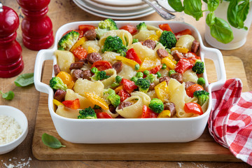 baked vegetable and sausages lumaconi pasta in white baking dish