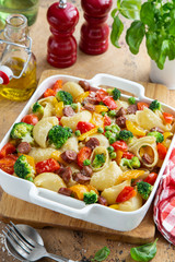 baked vegetable and sausages lumaconi pasta in white baking dish
