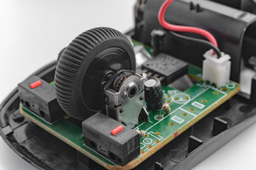 The broken internal parts of the wireless mouse for computer are open for repair. Circuit board and...