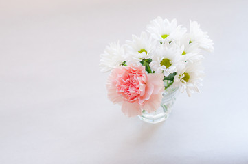 ピンクのカーネーションと白い菊の小さなブーケ トップビュー 左にコピースペース 白背景