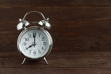 Retro alarm clock on an old dark wooden background.