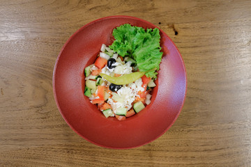 Restaurant food served on a red plate. Fish, cheese, salad, vegetables, sauce.
