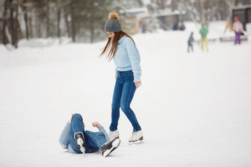 Couple learn to skate in winter park outside.