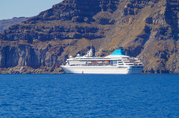 White classic Celestyal Cruises cruiseship or cruise ship liner anchored in bay of volcanic Greek...