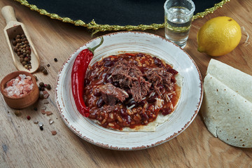 Traditional Mexican Tacos with Beans, Chili Peppers, beef in white ceramic plate on wooden background. Tasty Chili con carne beef burritos in corn tacos