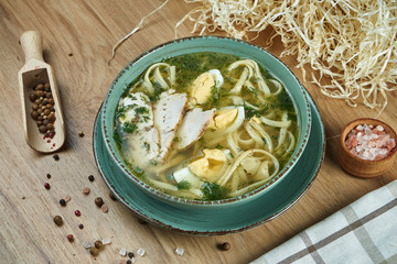 Dietary soup with chicken, vegetables and parsley in compostion with ingridients on wooden background in blue ceramic bowl. Top view tasty soup. Flat lay food