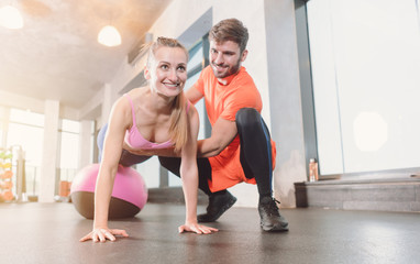 Woman with personal trainer in the gym doing pushups