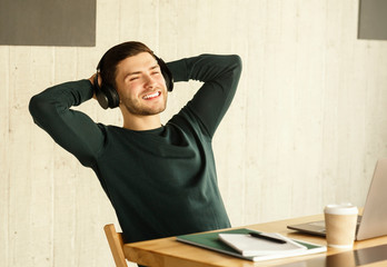 Obraz premium Freelance Guy In Headphones Procrastinating Relaxing Sitting In Modern Office
