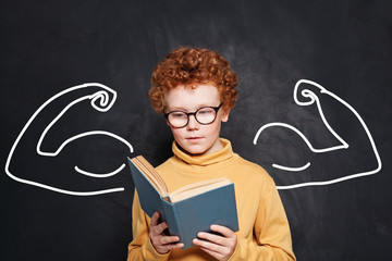Smart kid student wearing glasses holding book on black