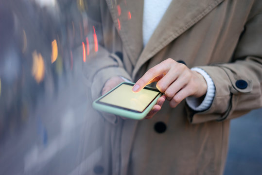 Closeup photo of female hands with smartphone. Night street on background