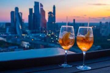 Glasses with a cocktail on the background of the city. Rendezvous for two. Rendezvous at the rooftop restaurant. Restaurant overlooking downtown. Romantic setting. Moscow. Russia. Slices of orange.