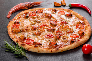 Tasty sliced pizza with seafood and tomato on a concrete background
