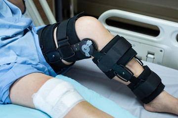 Asian woman patient with bandage compression knee brace support injury on the bed in nursing...