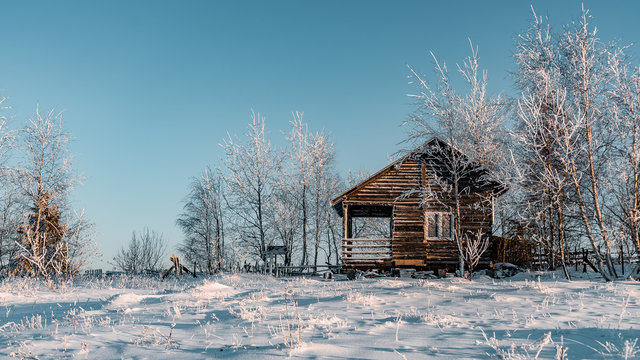 Winter season, landscape picture of a holiday house covered by snow at sunset, country landscape with timber fence