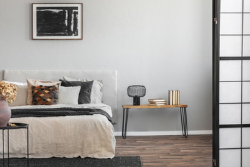 Abstract black oil painting in frame on empty beige wall of cozy bedroom