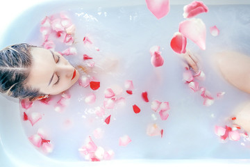Naklejka na ściany i meble Young sexy girl taking a milk bath with rose petals closeup