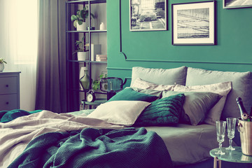 Cozy bed with pillows and blankets in emerald and grey colors